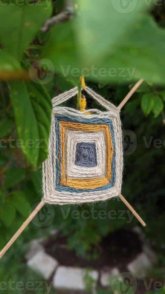 Crafted with care and colorful thread, this hanging decor brings boho charm to tree shade, crafted symbol for DIY, and slow-living concepts. photo