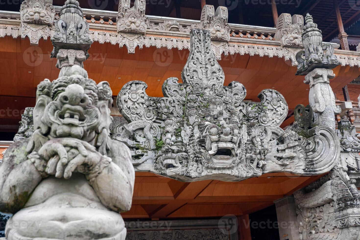 Close-up of a Balinese guardian statue and elaborately carved temple gate at a traditional building in Bali, Indonesia. photo