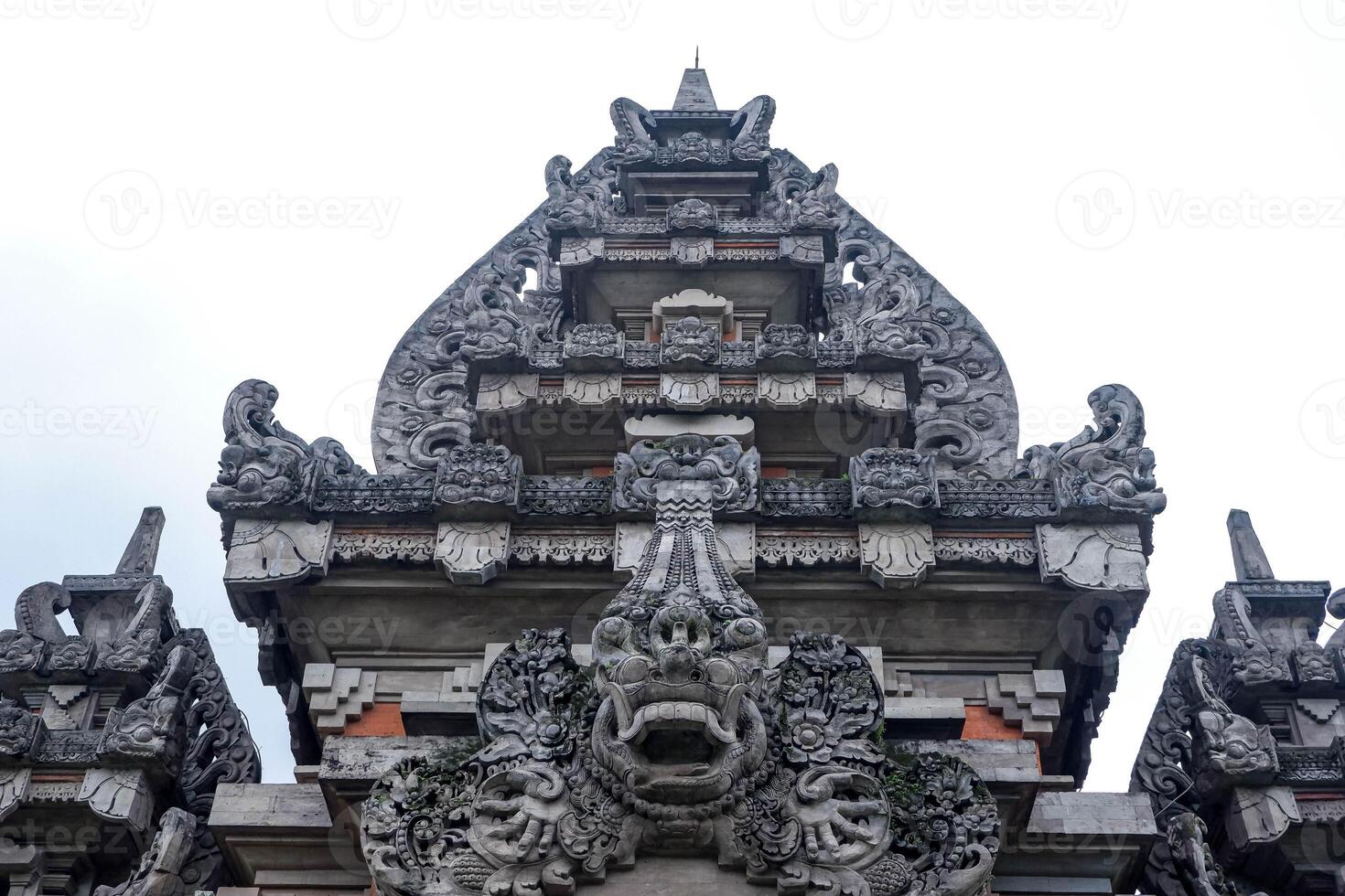 Front view of a traditional Balinese Hindu temple gate with intricate stone carvings and sacred symbolism in Bali, Indonesia. photo