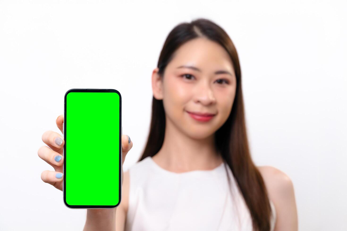 Beautiful Asian businesswoman shows a blank screen of mobile phone. She smiles at the camera photo