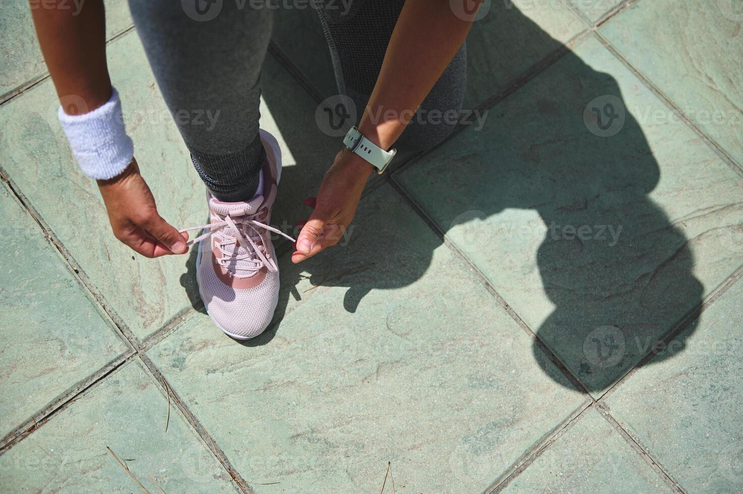 Close-Up of Athlete Tying Shoelaces on Outdoor Green Tiled Ground photo