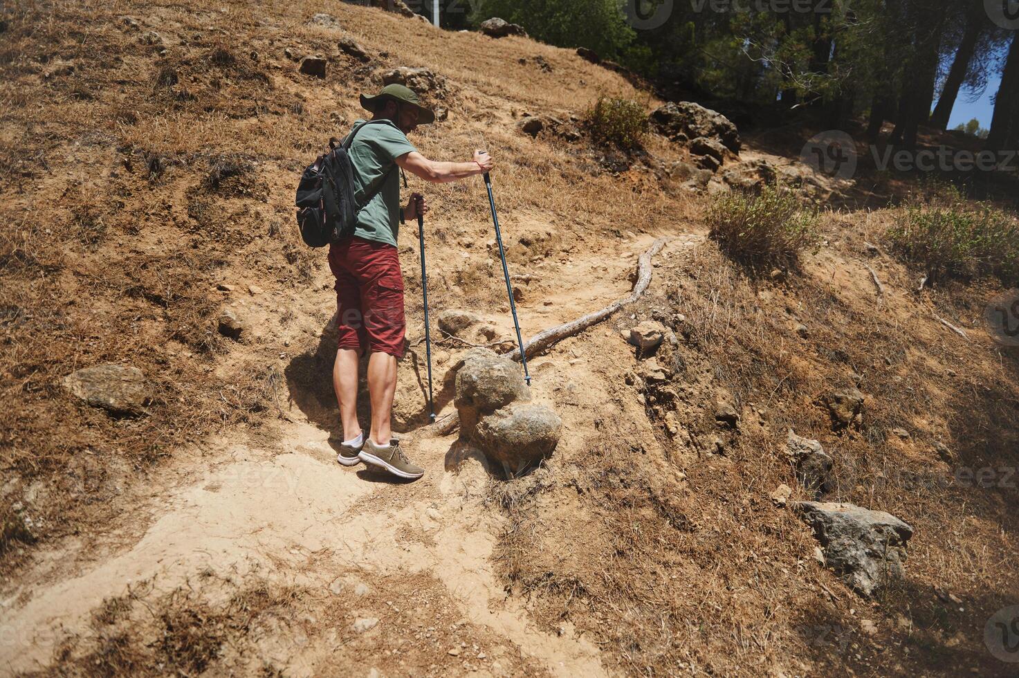 Man Hiking Through a Sunlit Rocky Mountain Trail with Backpack photo