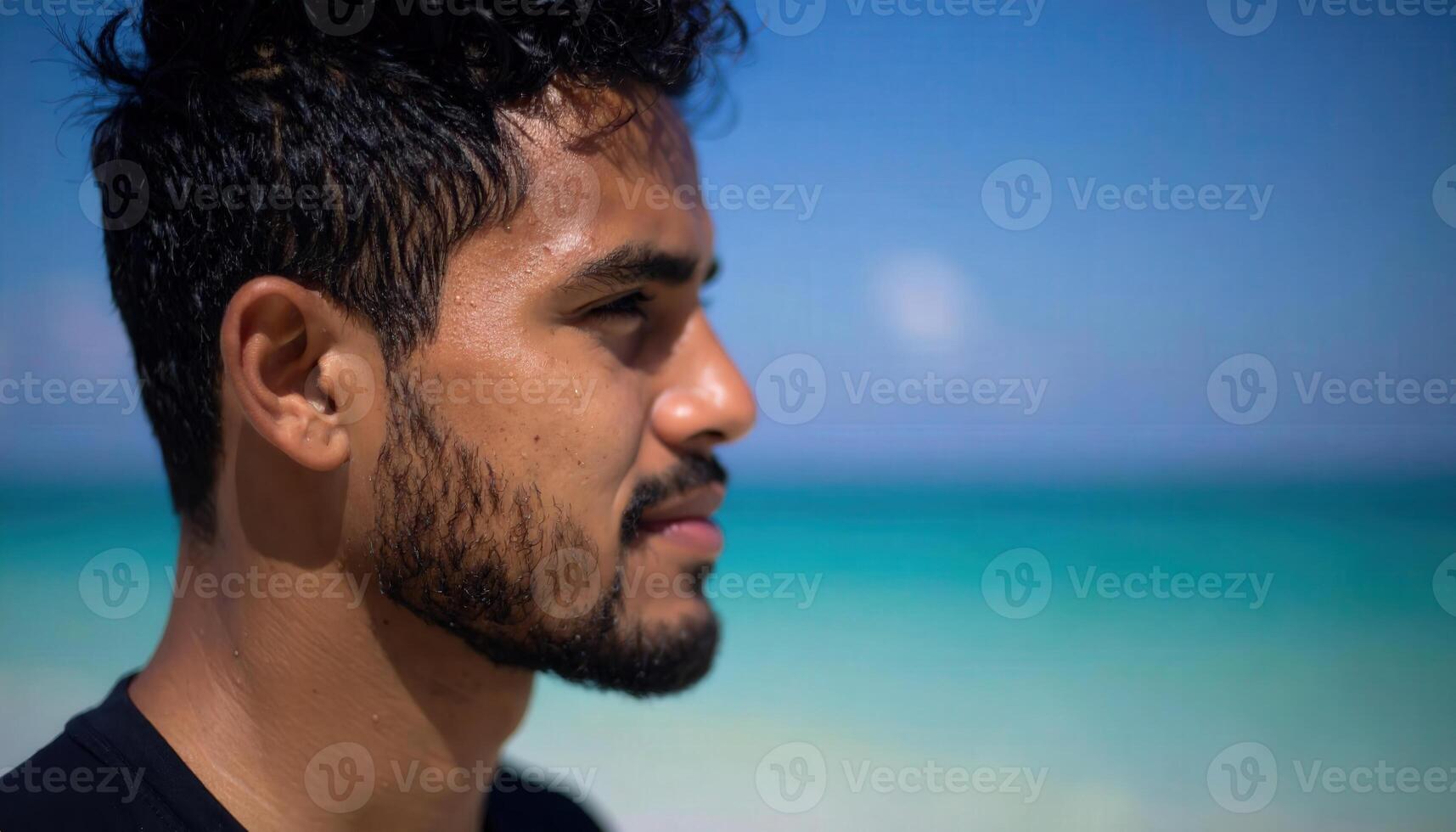 A man with a beard and a black shirt on the beach photo