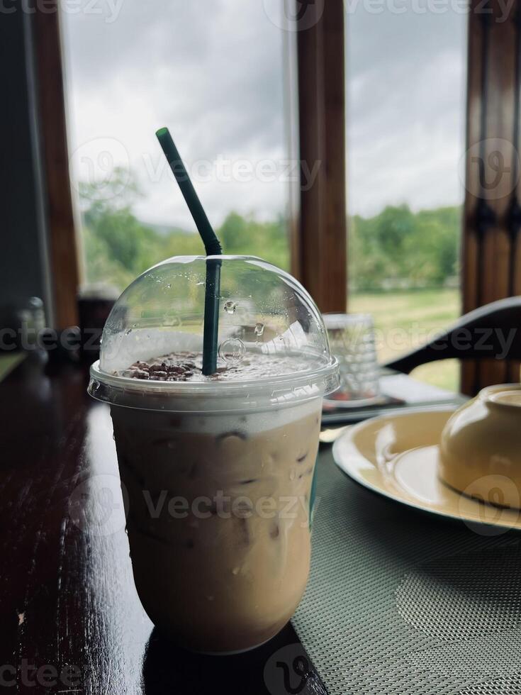 A iced coffee with a straw sitting on a table photo