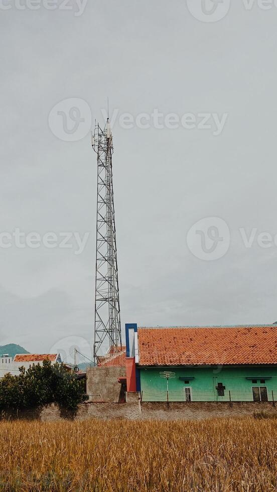 A small building with a cell tower in the middle of a field photo