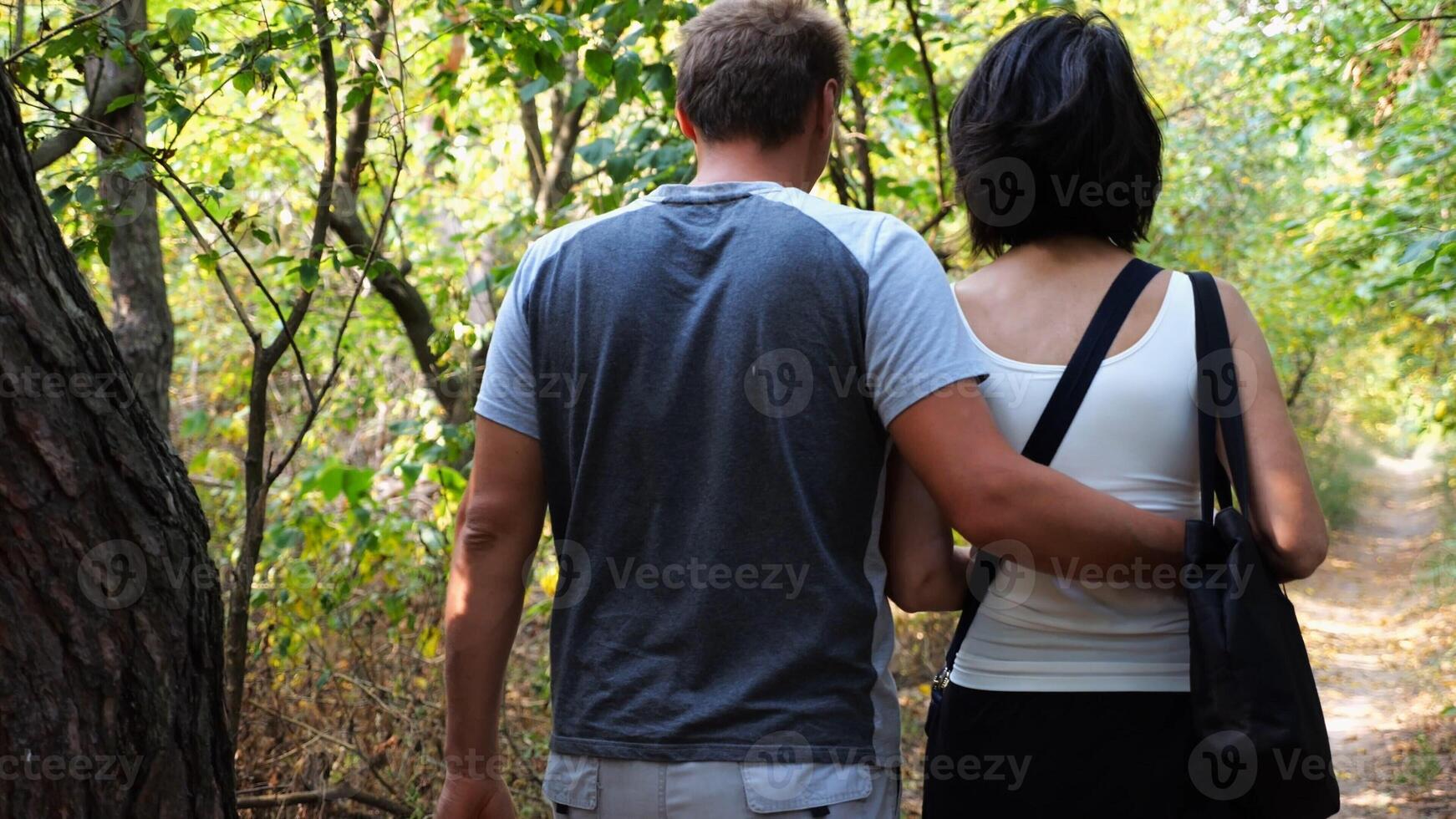 Happy couple walking along path at summer forest.Romantic pair going along trail at wild woodland. Lovers spending time together at nature. Concept of love and happiness. Slow motion photo