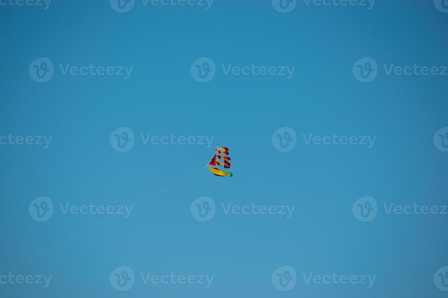 Kite Festival. Ship-Shaped Kite with Red Sails Against Clear Blue Sky photo