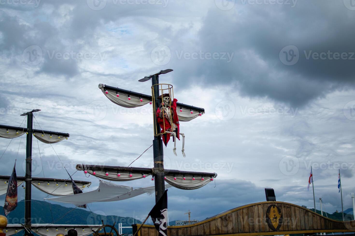 Pirate Ship Display with Skeleton in Mast Cage Under Moody Sky photo