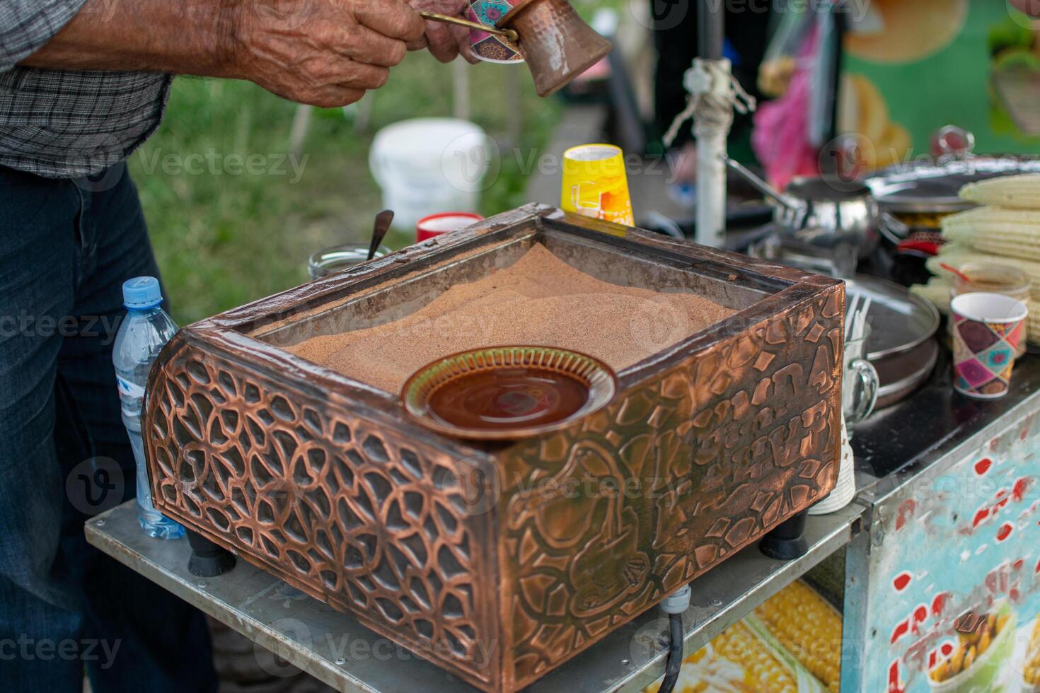 Brewing Traditional Coffee over Hot Sand with Copper Pot photo