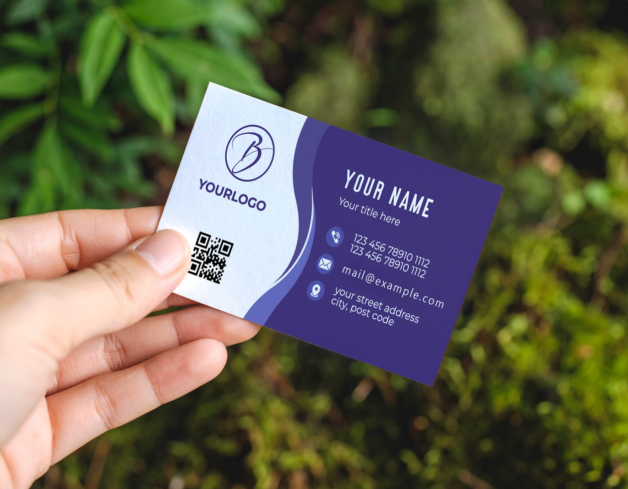 Hand Holding Business Card Mock Up Against Green Foliage Background psd