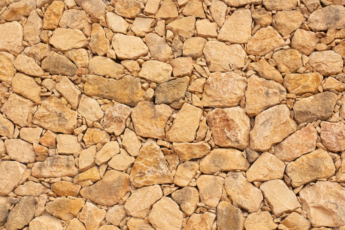 Natural stone wall texture in Spain with warm tones and varied shapes enhances the rustic charm of the landscape photo