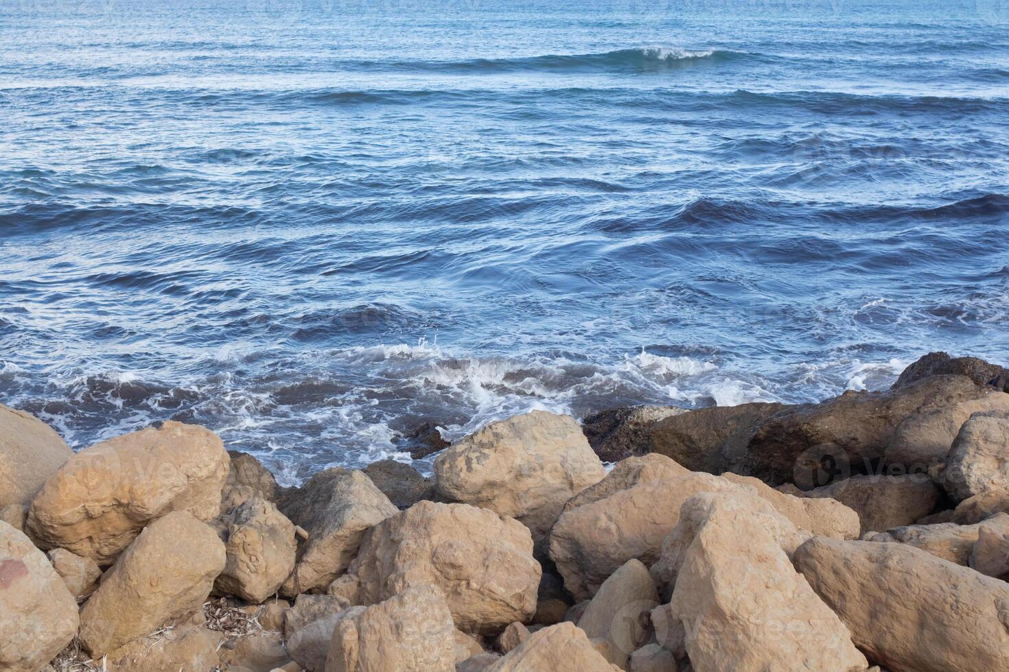 Coastal rocks and waves along the beautiful shores of Spain during a calm day in late afternoon photo