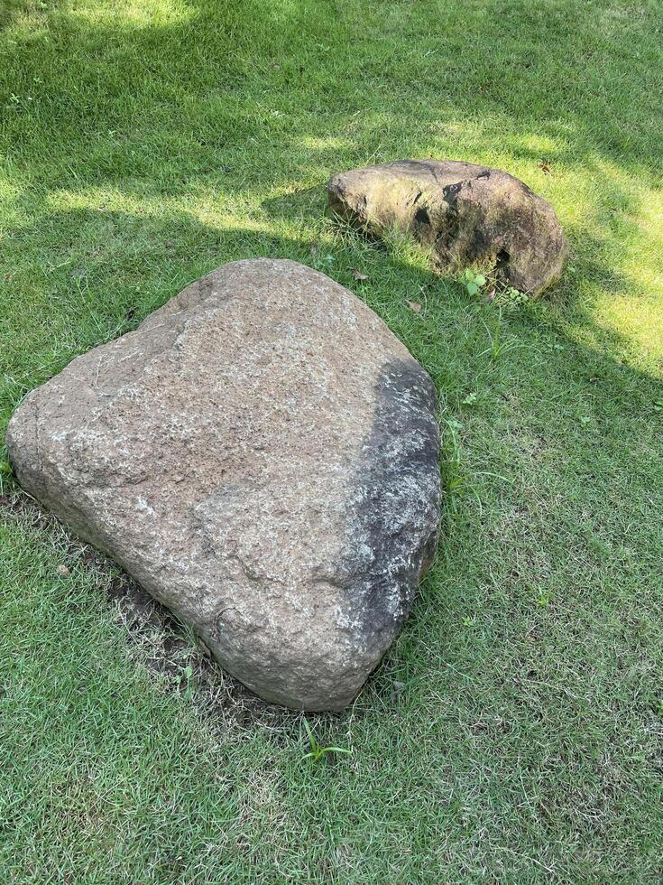 Large Natural Boulders Resting on a Vibrant Green Grass Lawn with Sunlight and Shadow photo
