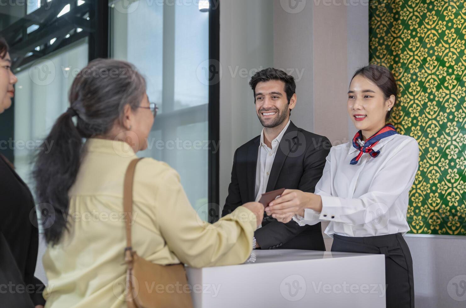 airline officers return passport to passenger that standing in queue,ground attendants working at airport check-in area,airlines service photo