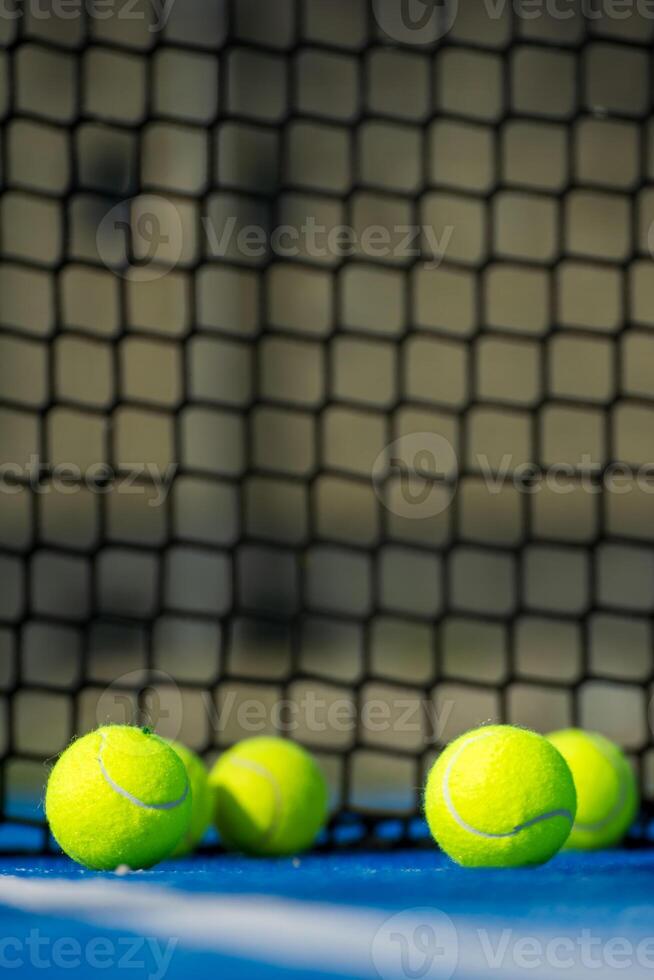 Selective focus. Net of a blue paddle tennis court and four balls near the white line. Selective focus. photo