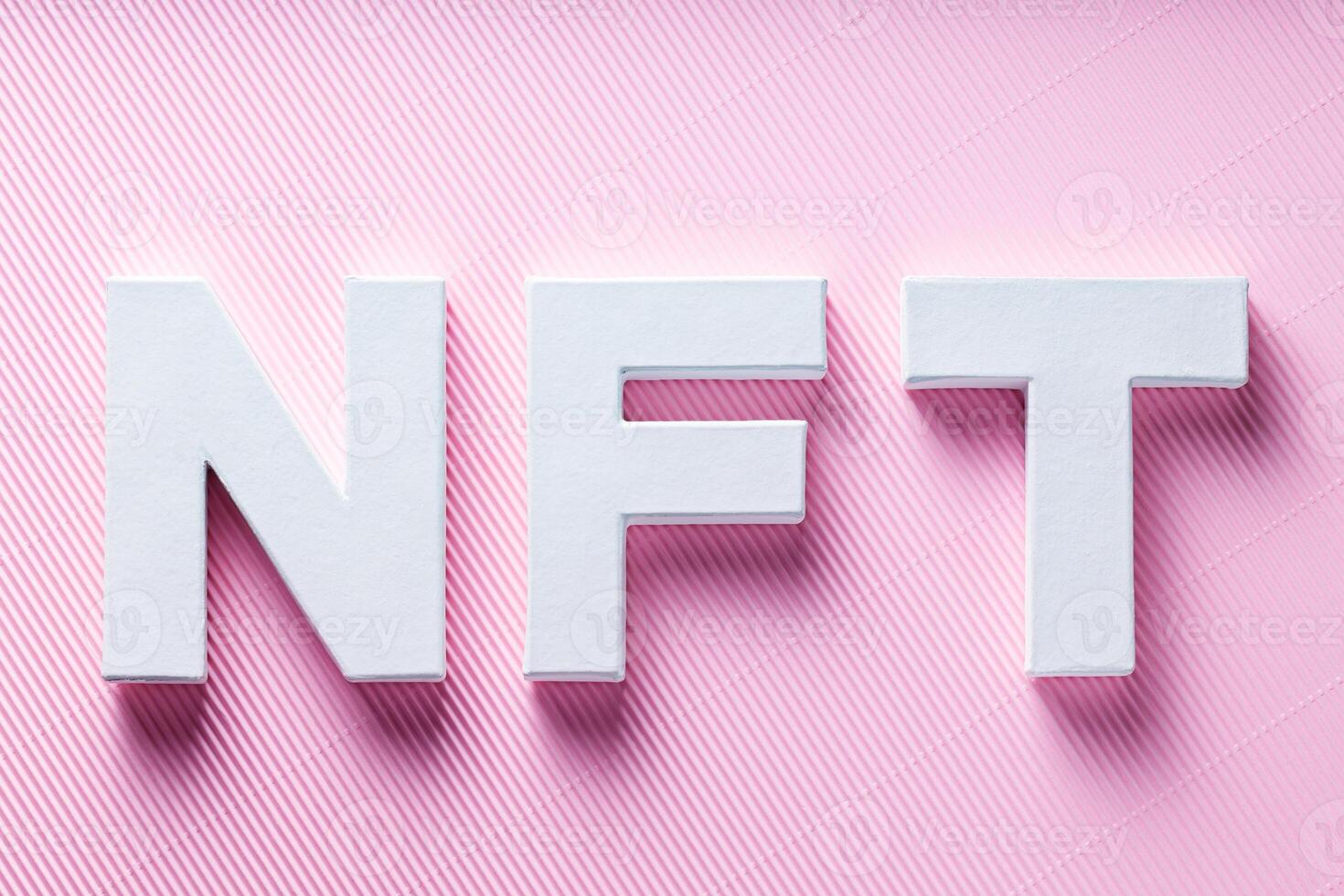 NFT White Letters on Pink Diagonal Striped Background, Crypto Art Concept, Top View photo