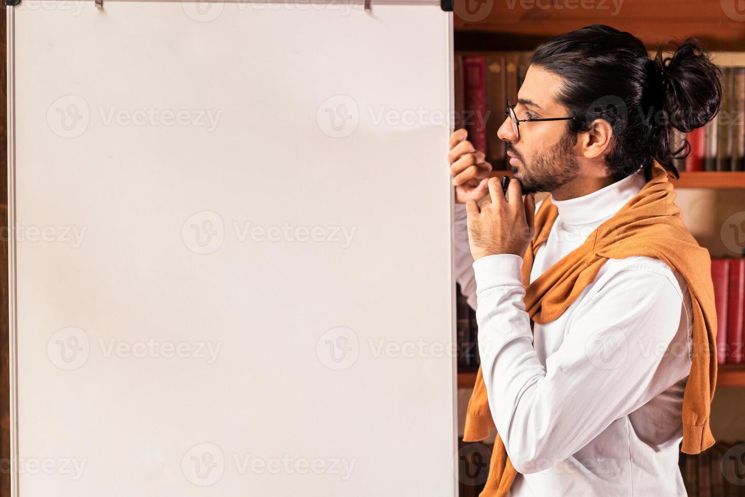 E-Teaching Concept. Thoughtful Indian Teacher Man Standing Near Blackboard With English Grammar Rules Teaching Student Online Indoor. Remote E-Learning And Modern Education photo