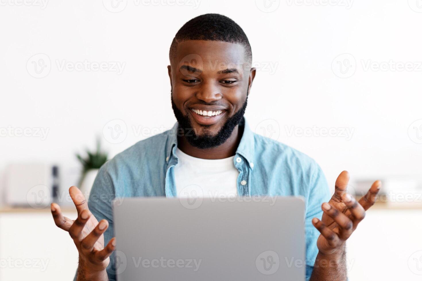 Web Conference. Cheerful Millennial African American Man Having Call On Laptop, Smiling Black Guy Sitting At Desk With Computer, Taking And Gesturing At Camera, Enjoying Online Communication photo