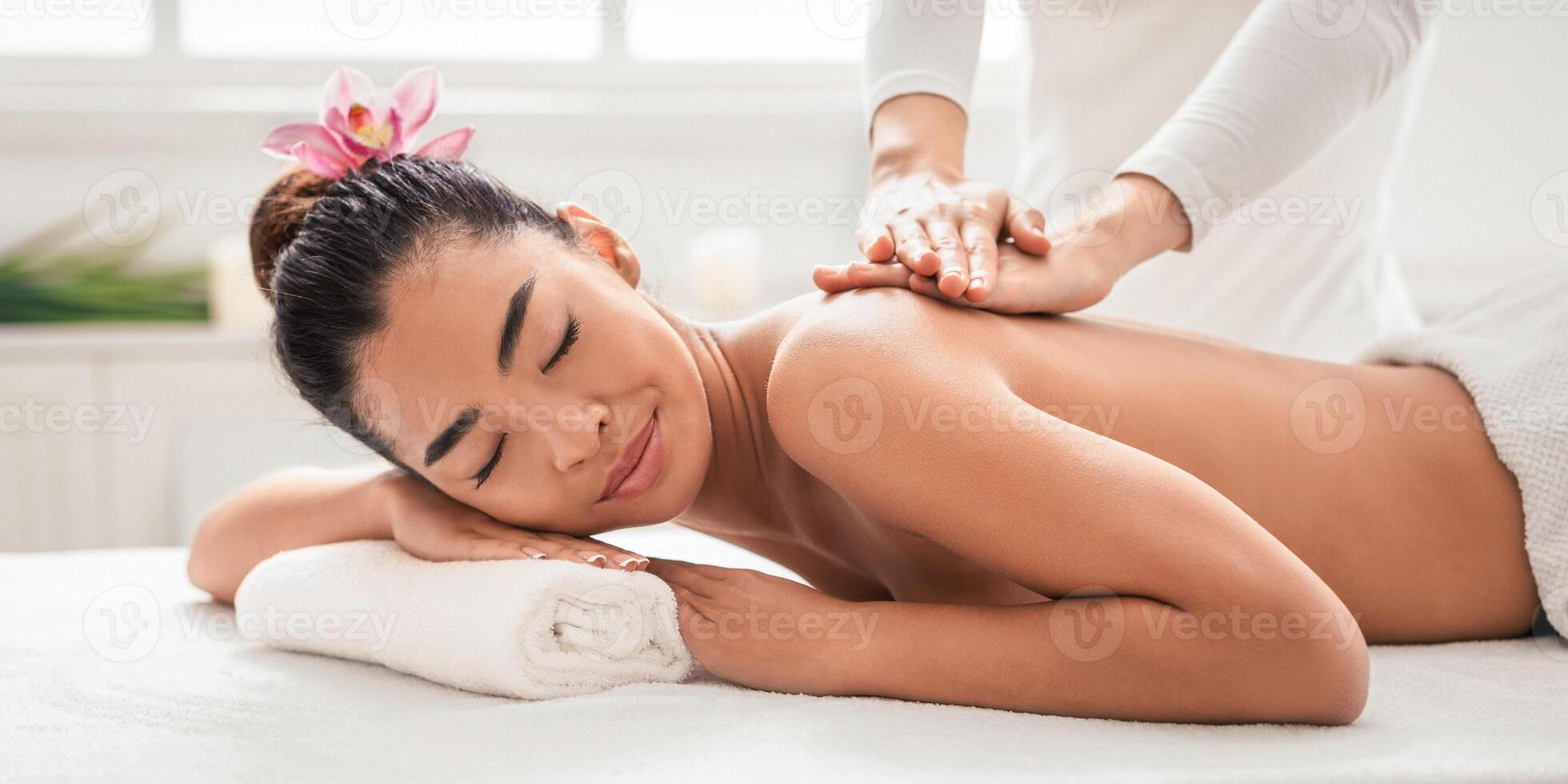 Back Massage. Beautiful asian woman getting body treatment by professional masseur in spa salon, relaxed korean female enjoying beauty and wellness day, lying with closed eyes, closeup with free space photo