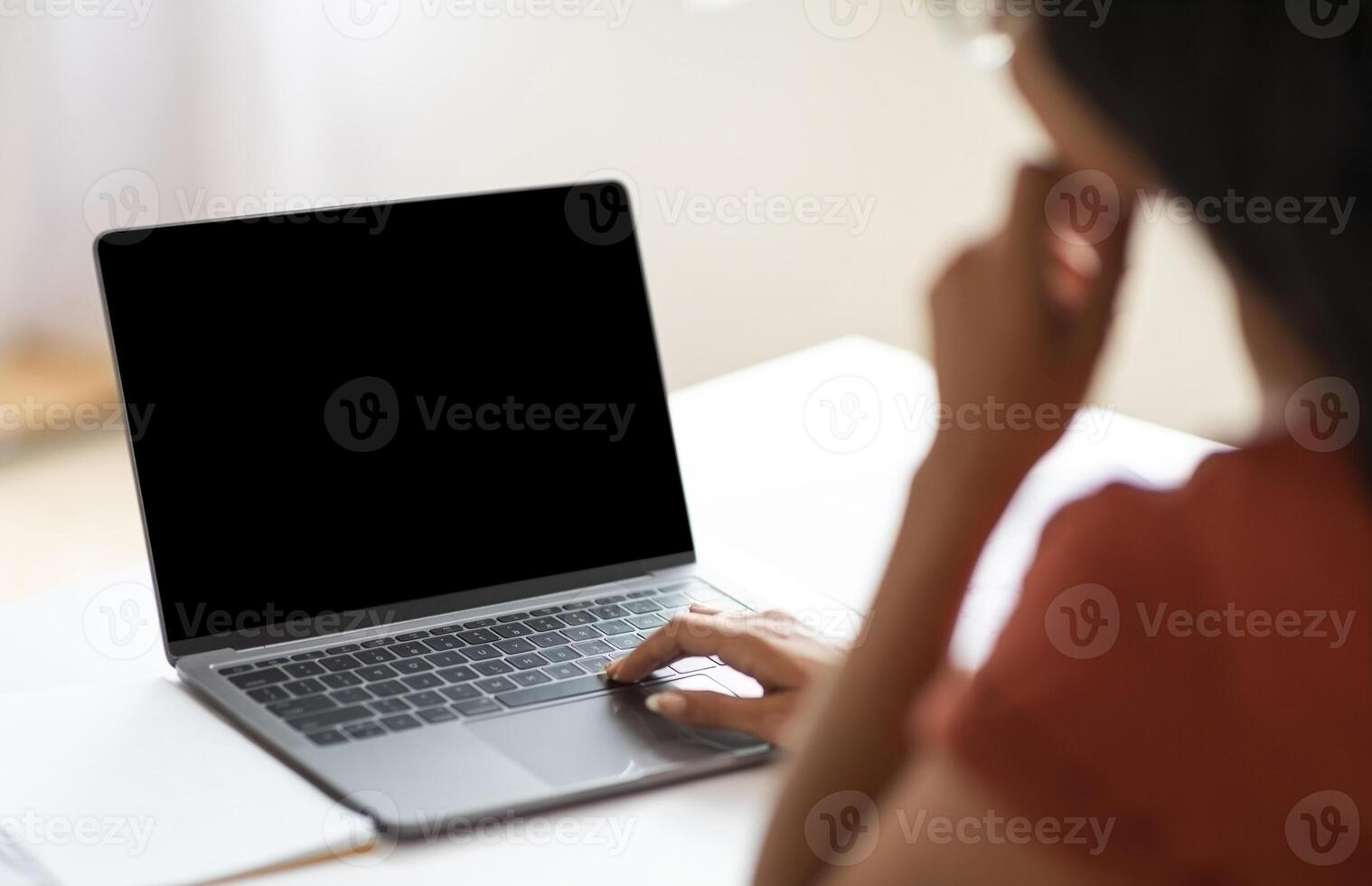 Over shoulder shot of unrecognizable businesswoman working on laptop with black empty screen, hands typing on computer keyboard while working in office, cropped image photo