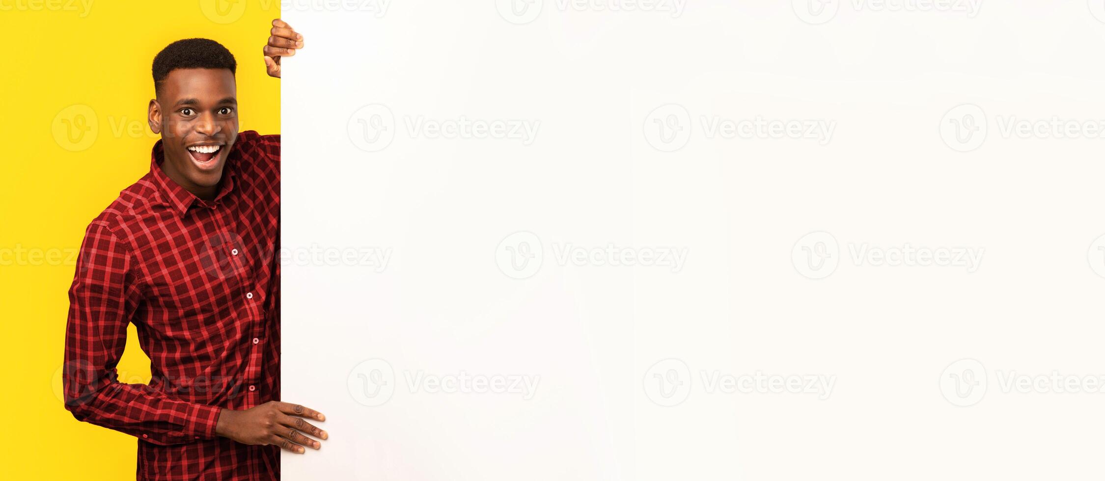 Excited Black Guy Holding Blank White Advertisement Board, Positive African Man Demonstrating Free Copy Space For Your Text Or Design, Standing Isolated Over Yellow Studio Background photo