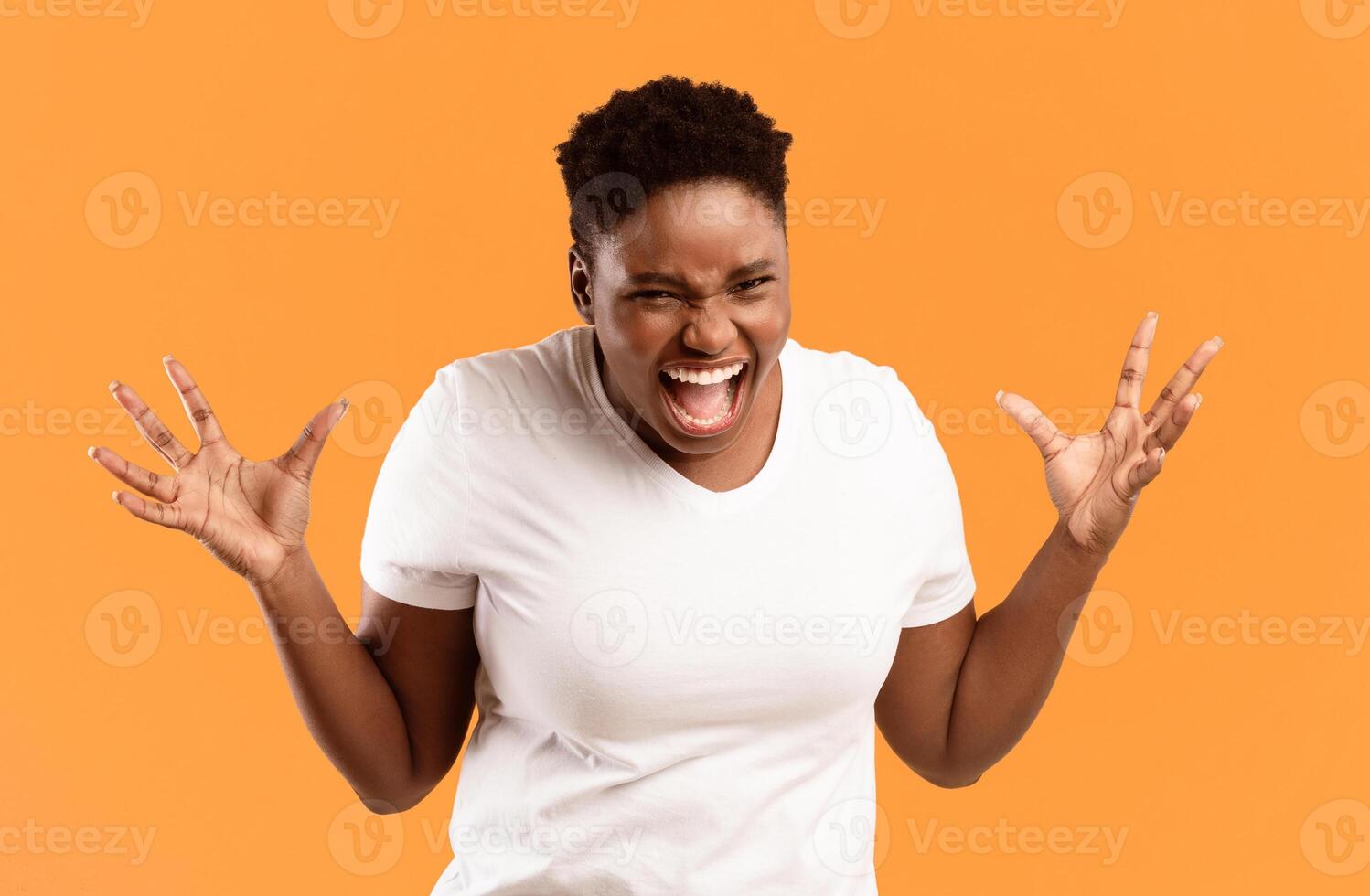 Angry Plus-Size African American Lady Shouting Freaking Out Standing Posing Over Yellow Studio Background, Looking At Camera Angrily. Negative Emotion, Madness And Anger Concept photo
