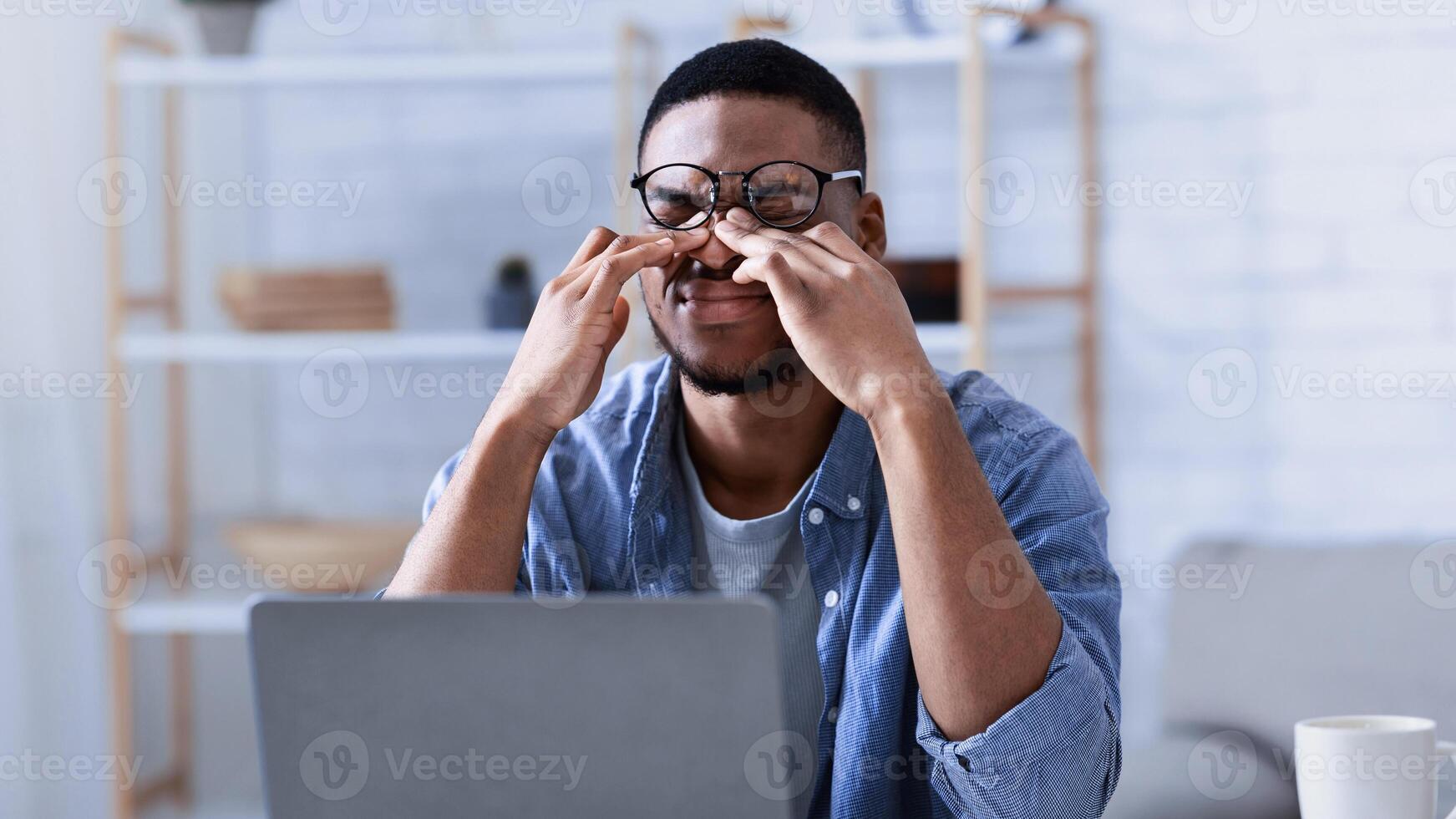 Glaucoma. African American Man Massaging Tired Eyes Suffering From Eyestrain And Fatigue, Exhausted After Work On Computer Sitting At Workplace In Office. Eye Sight Problem Concept photo
