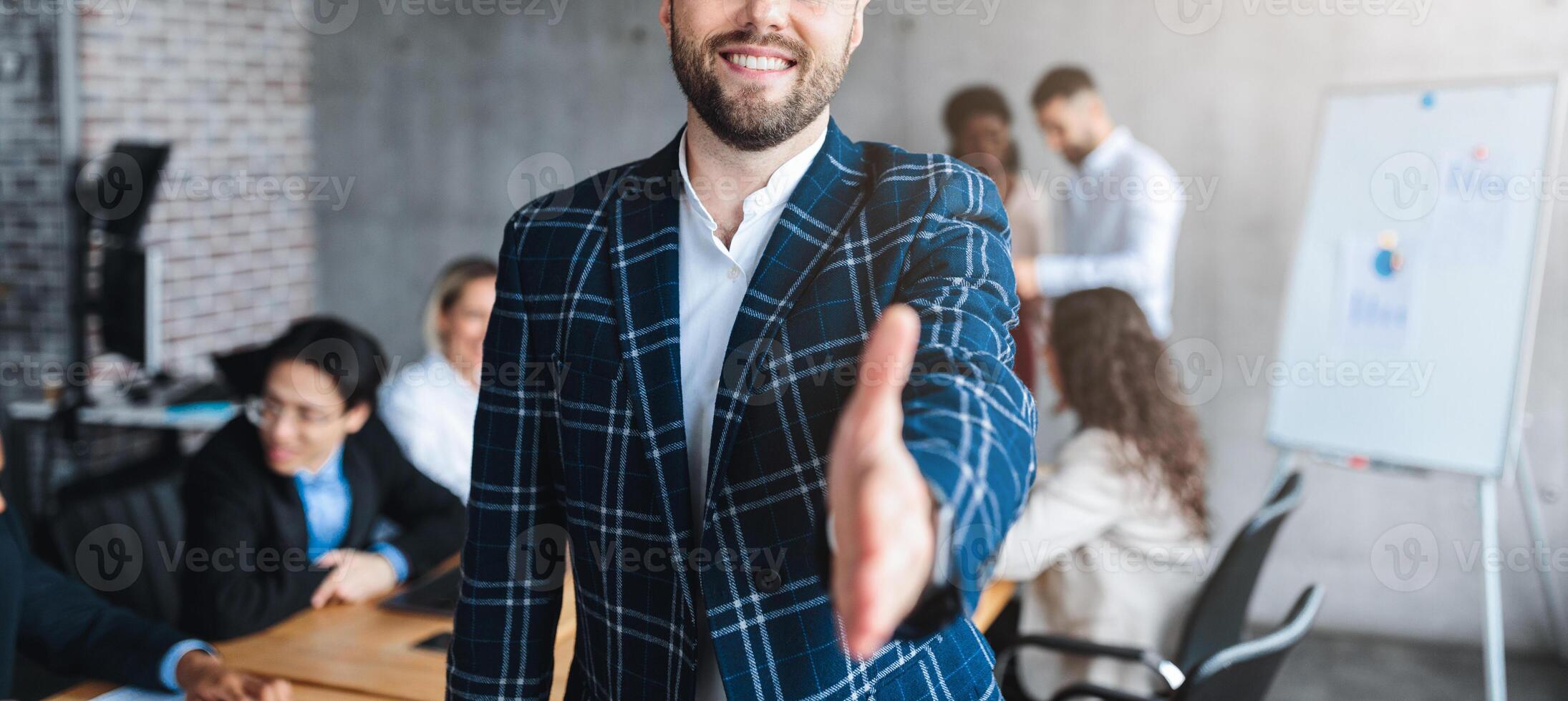 Successful Young Entrepreneur Stretching Hand For Handshake Greeting Smiling To Camera Standing In Modern Office. Employment And Business Career Offer Concept. Selective Focus photo