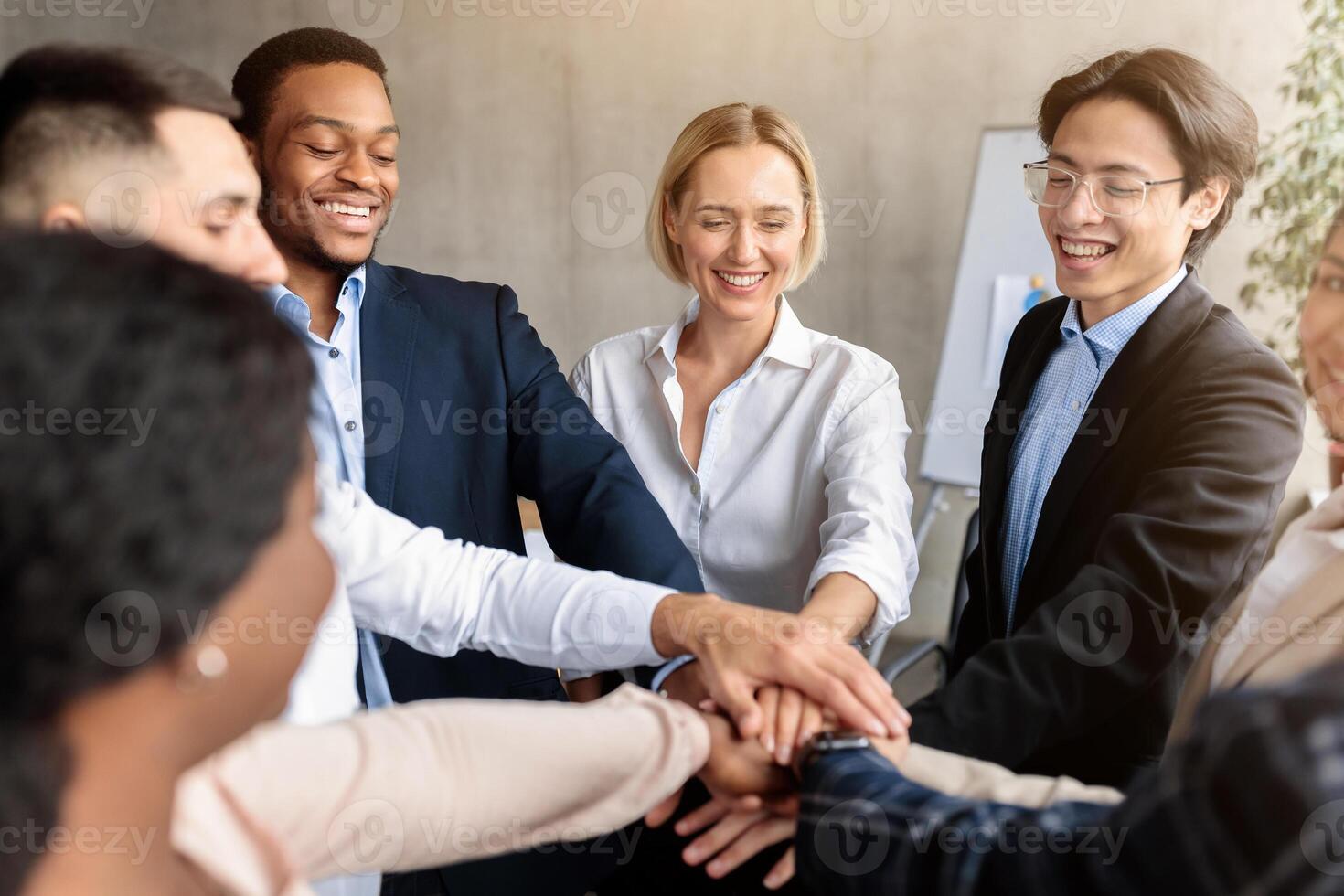 Teamwork And Teambuilding. United Business Team Holding Hands Standing In Circle In Modern Office. Diverse Businessmen And Businesswomen Coworkers Posing Together At Corporate Meeting Indoors photo