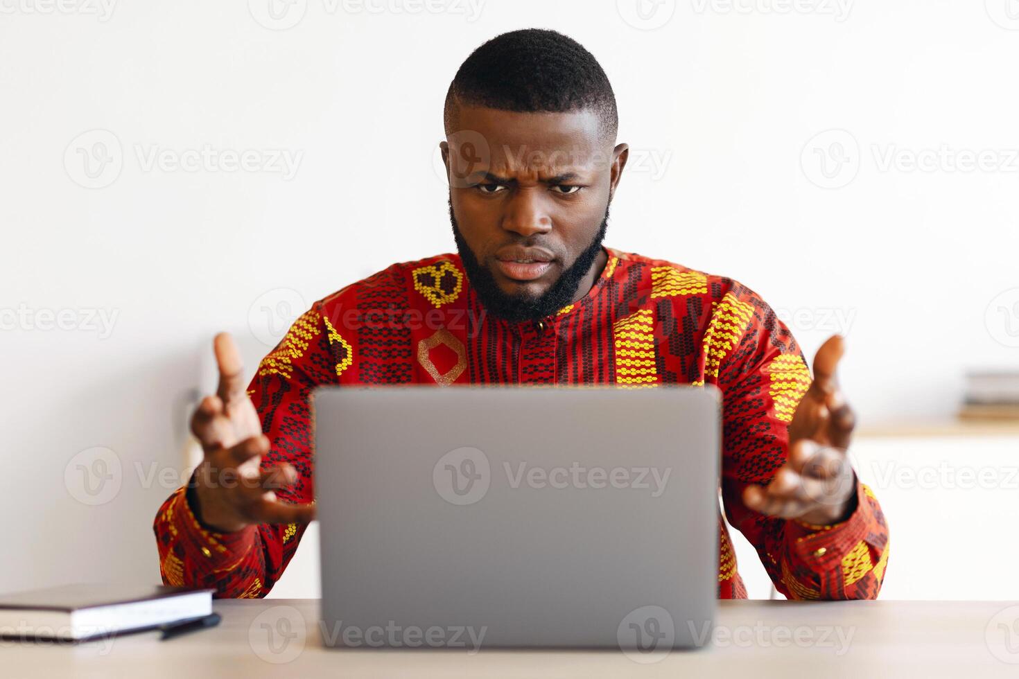 Computer Problems. Frustrated African Businessman In Traditional Clothes Having Troubles With Laptop In Office, Black Guy In Ethnic Shirt Raising Hands Emotionally Reacting To Bad Internet Connection photo