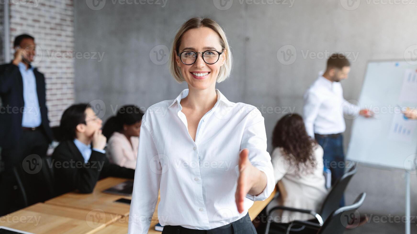 Female HR Manager Stretching Hand For Handshake Greeting To Camera Standing In Modern Office. Career Offer, Recruitment And Employment, Human Resources Concept. Selective Focus photo