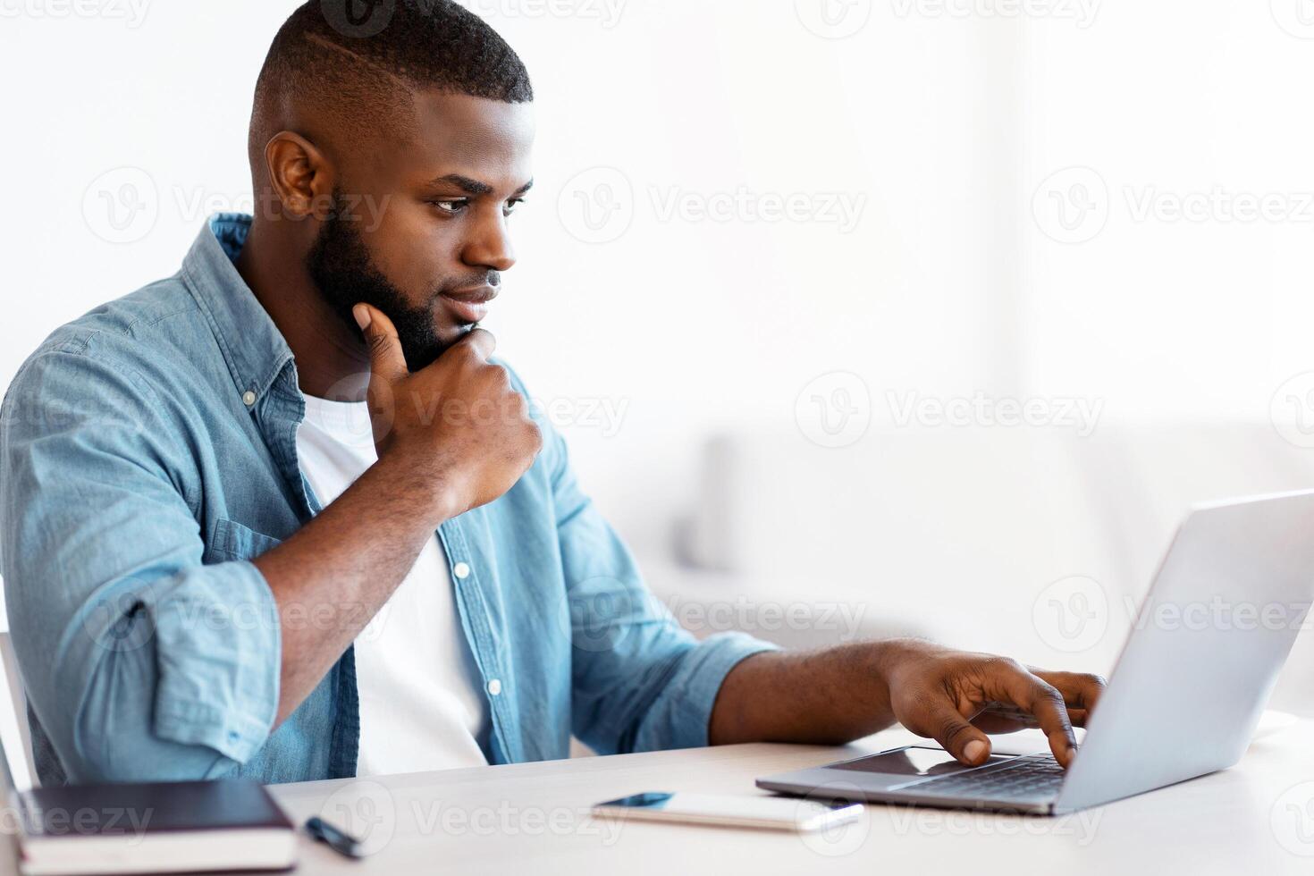 Distance Job. Millennial Black Freelancer Guy Working With Computer At Home Office, Young African American Man Sitting At Desk And Looking At Laptop Screen, Enjoying Remote Career, Copy Space photo