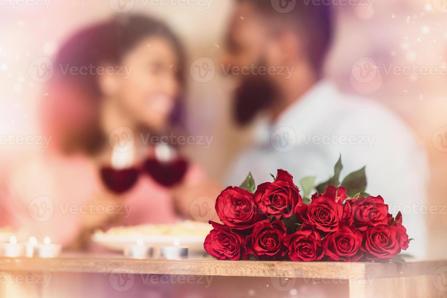 Romantic Date. Bouquet of flowers lying on the table, selective focus on red roses. African american couple spending time together at home or cafe, having dinner, drinking wine in blurred background photo