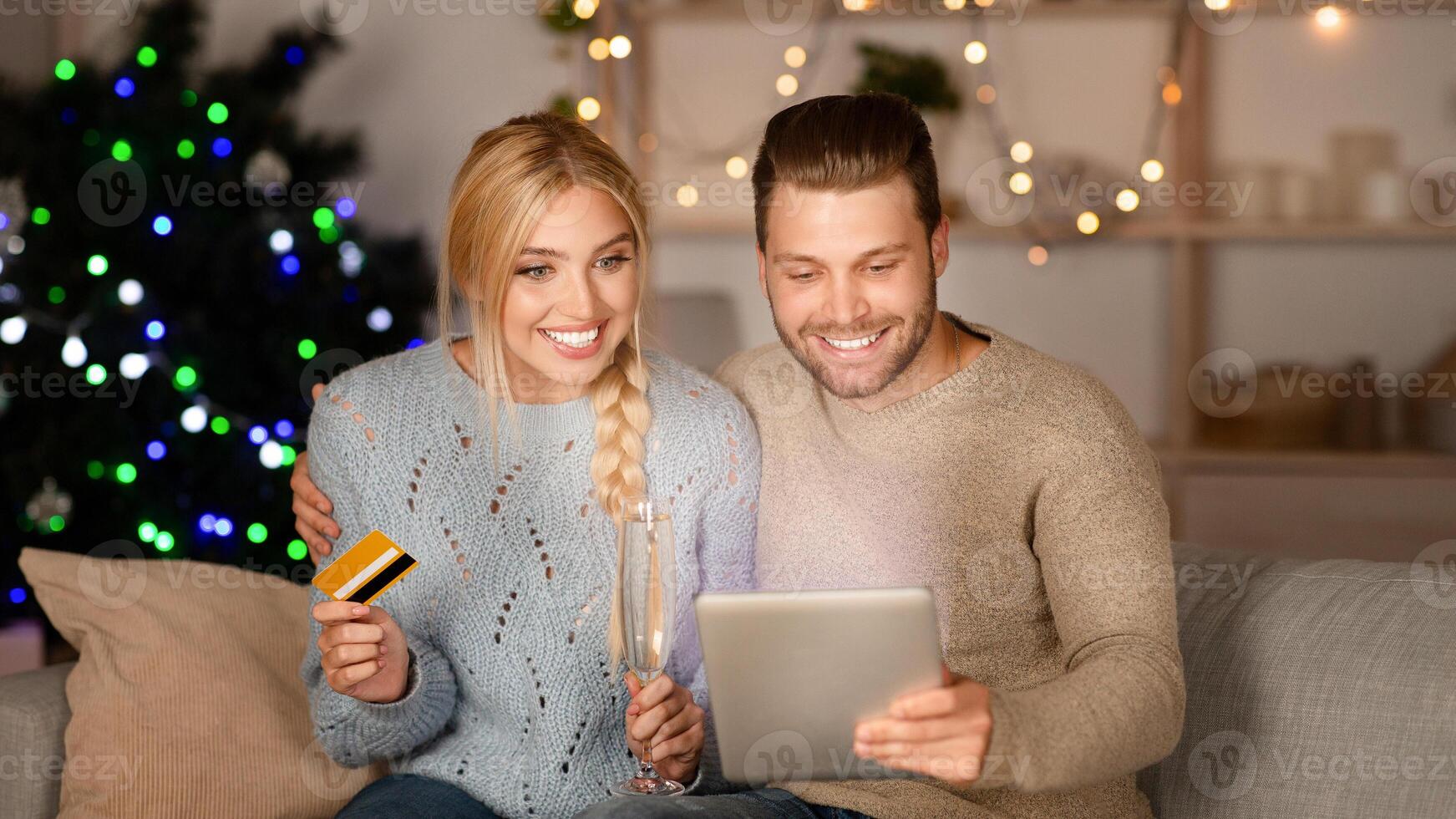 Happy couple doing Christmas shopping together, using digital tablet and credit card, copy space photo