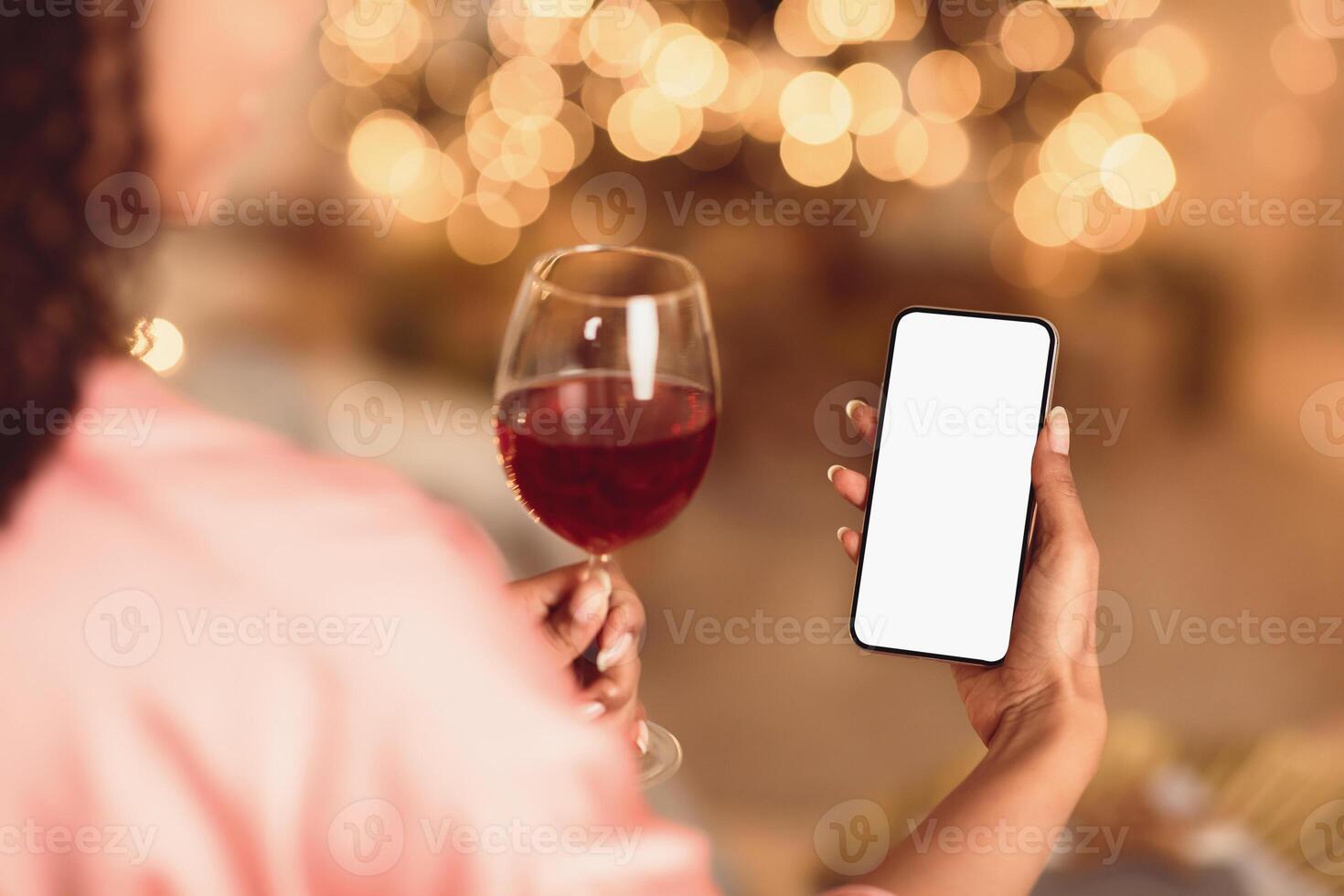 Online Date, Safe Meeting With Friends. Over The Shoulder Back View Of African American Woman Holding Phone With Blank Mockup Screen Talking By Chat Using Smartphone And Drinking Red Wine photo