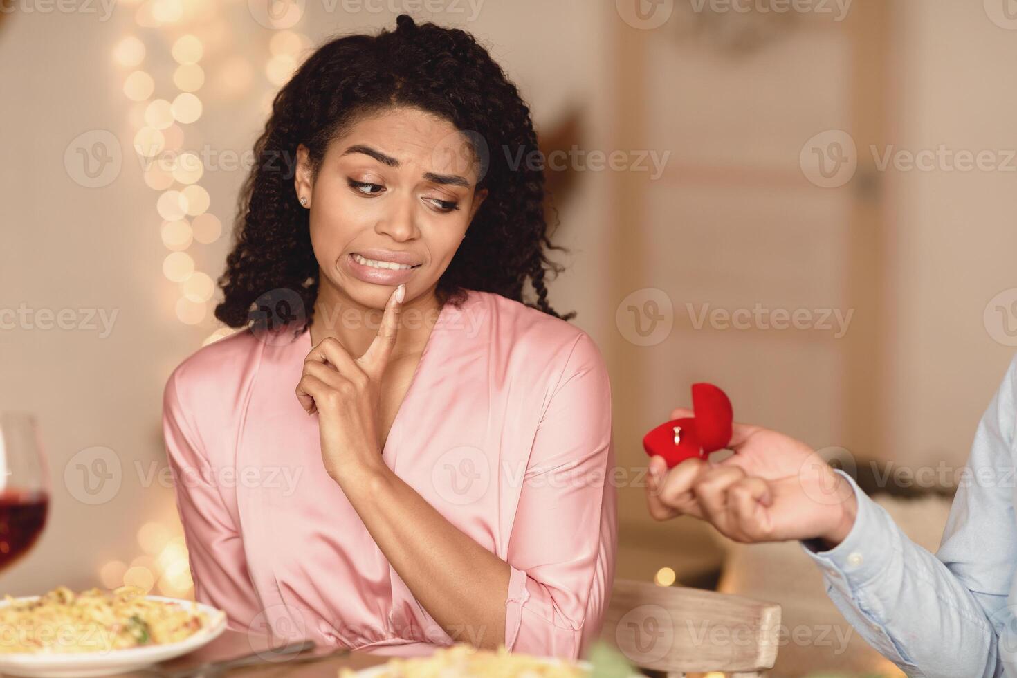 Proposal Failure. Confused african american woman in doubt looking at engagement ring, black man giving open box, uninterested lady saying no. Negative Reaction to Proposing. Disappointment Concept photo