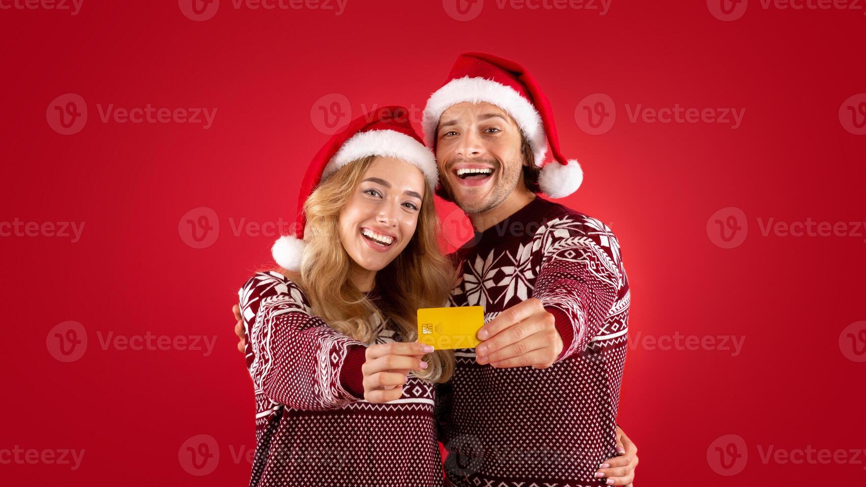 Shopping for Christmas. Smiling young couple showing contactless credit card over red background photo