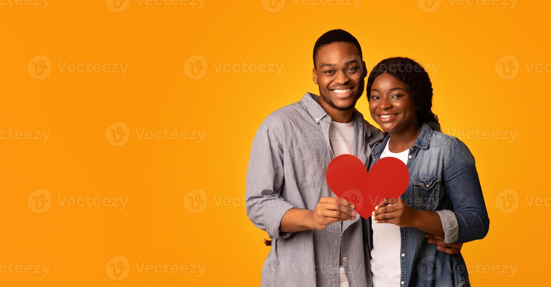 Joyful Loving Black Couple Holding Red Paper Heart And Hugging, Happy African American Man And Woman Celebrating Valentine's Day Together, Standing Isolated Over Yellow Background, Free Space photo
