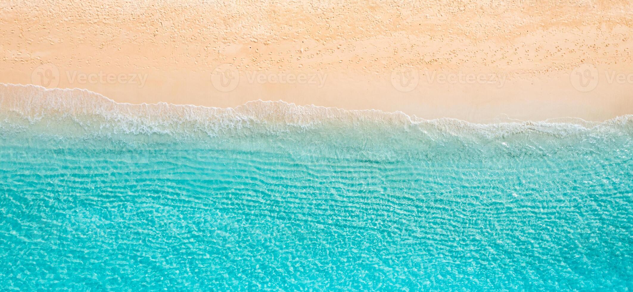 Drone shot top view sandy shoreline meeting calm blue ocean, natural textures and soft wave patterns, relaxing tropical seascape ideal for vacation imagery, beach backgrounds, peaceful design visuals photo