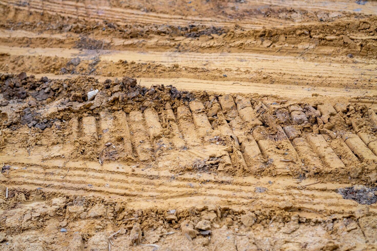 Excavated soil and heavy machinery tracks close-up action at urban construction site photo