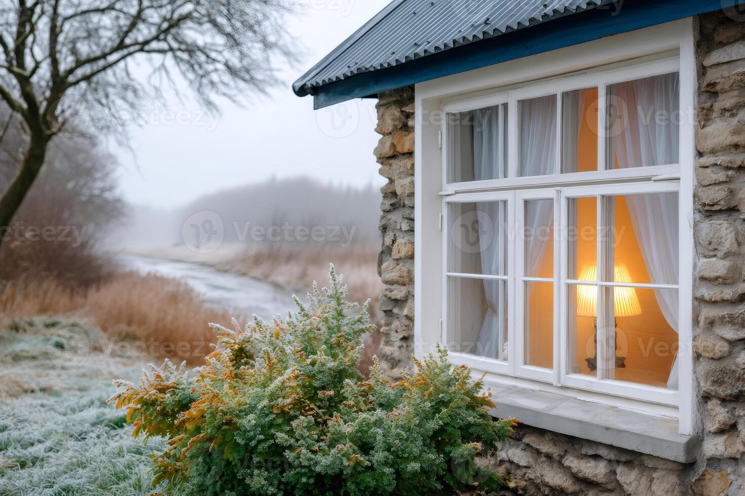 Warm light glowing in a window of a stone house overlooking a frosty landscape photo