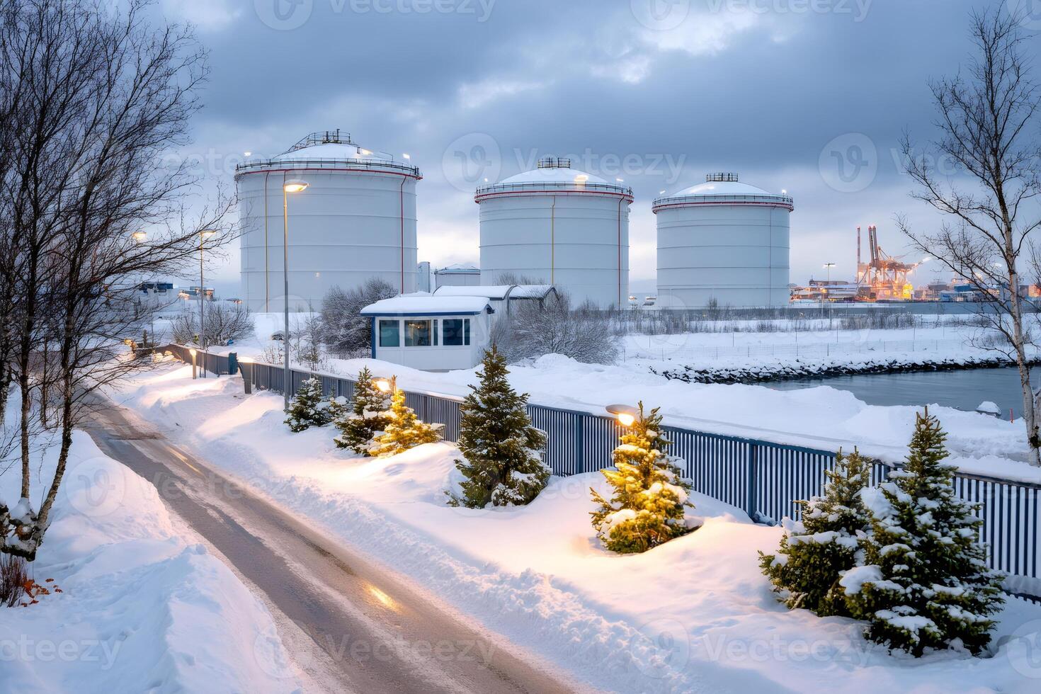 Large white cylindrical industrial tanks storing fuel in a snowy landscape photo