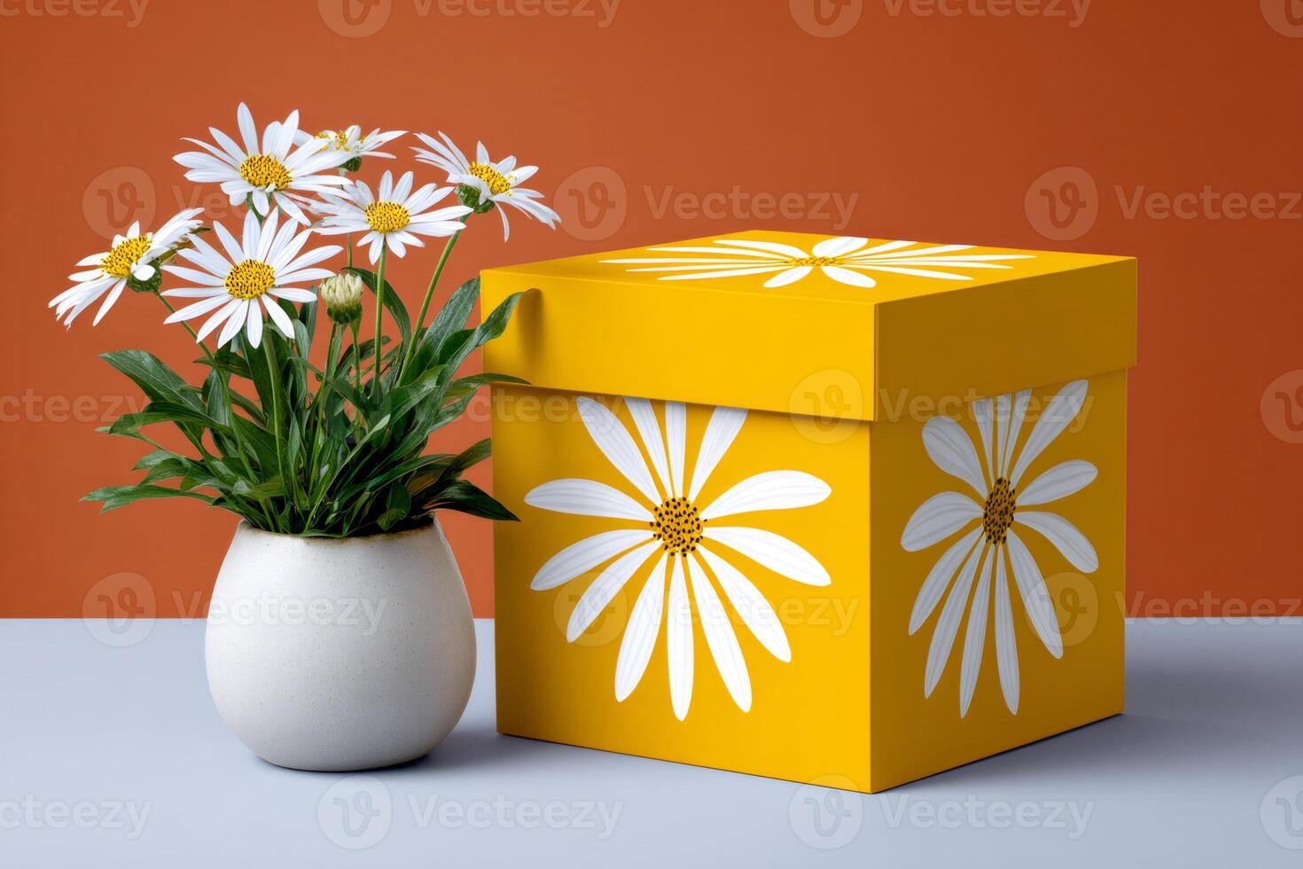 Yellow gift box with white daisy pattern and real daisies in a vase photo