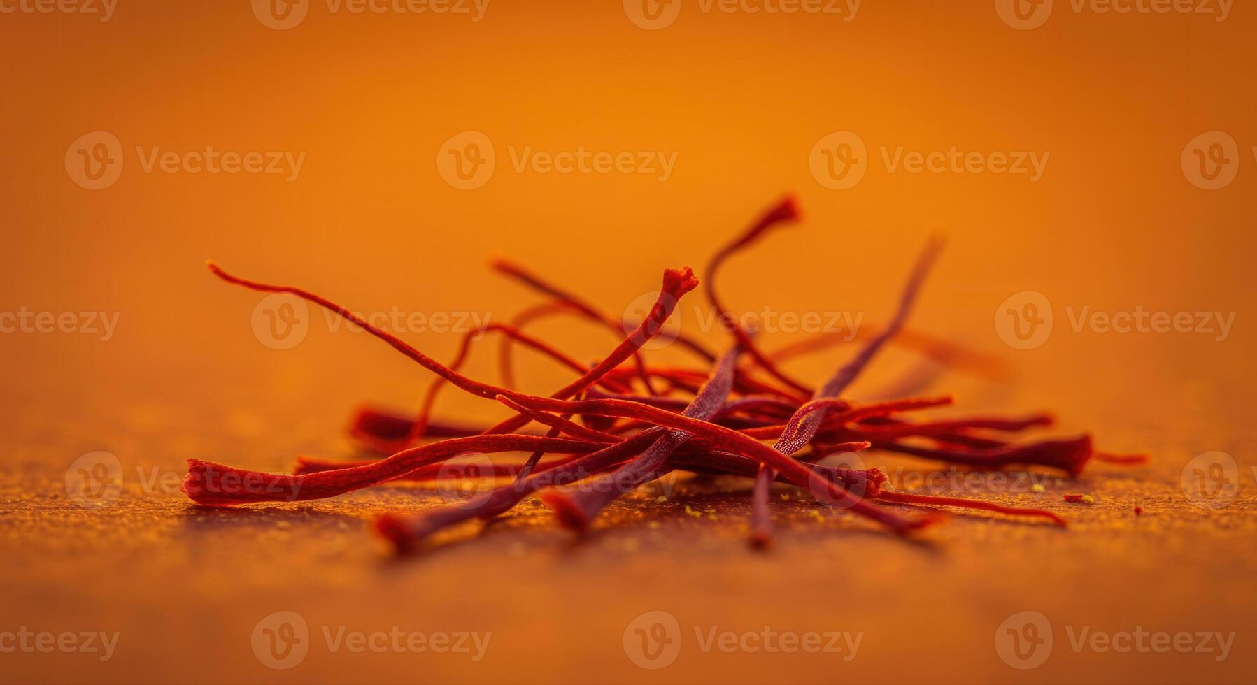 Pile of vibrant red saffron threads with an orange backdrop. photo