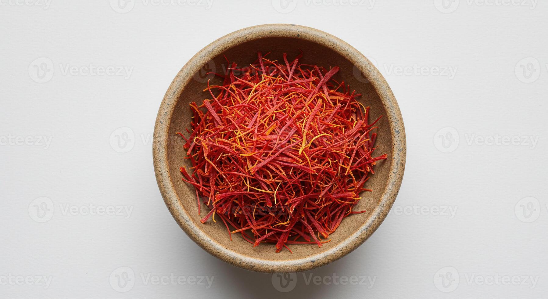 A bowl filled with vibrant red saffron threads on a white surface. photo