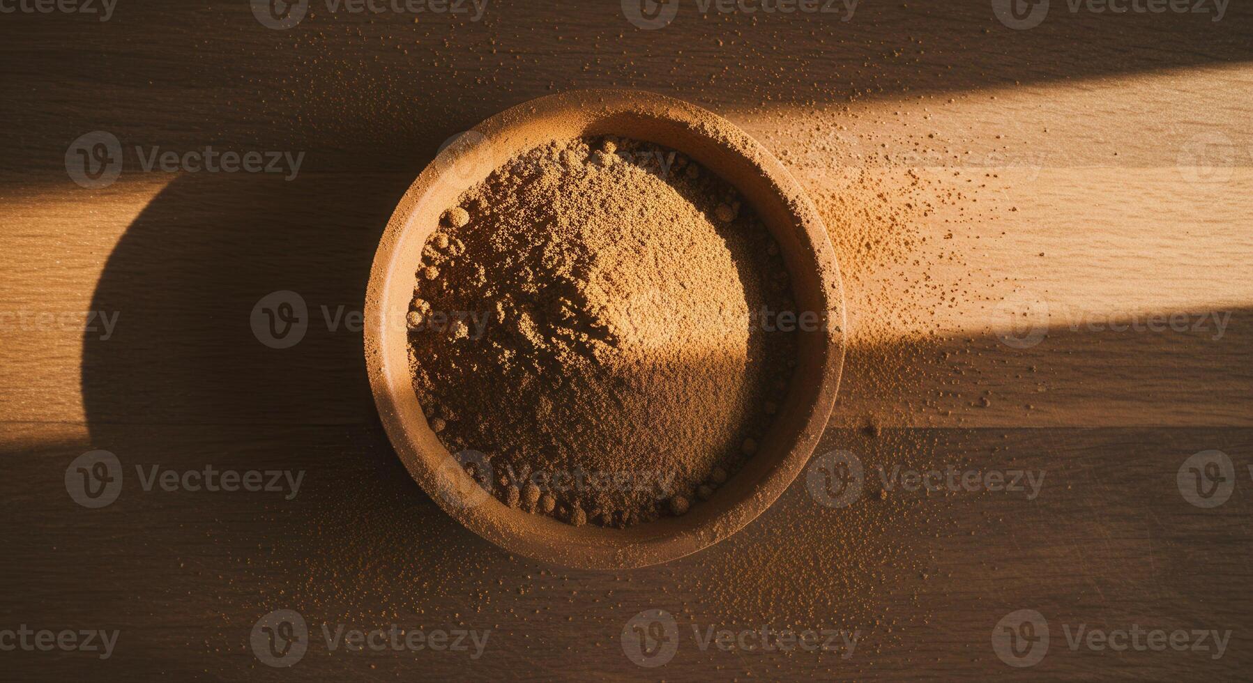 Overhead shot of a bowl of brown powder on a wooden table. photo