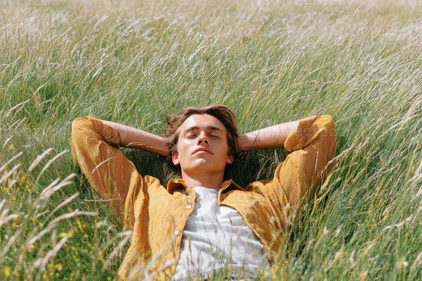 Young man relaxing lying in a field of tall grass photo