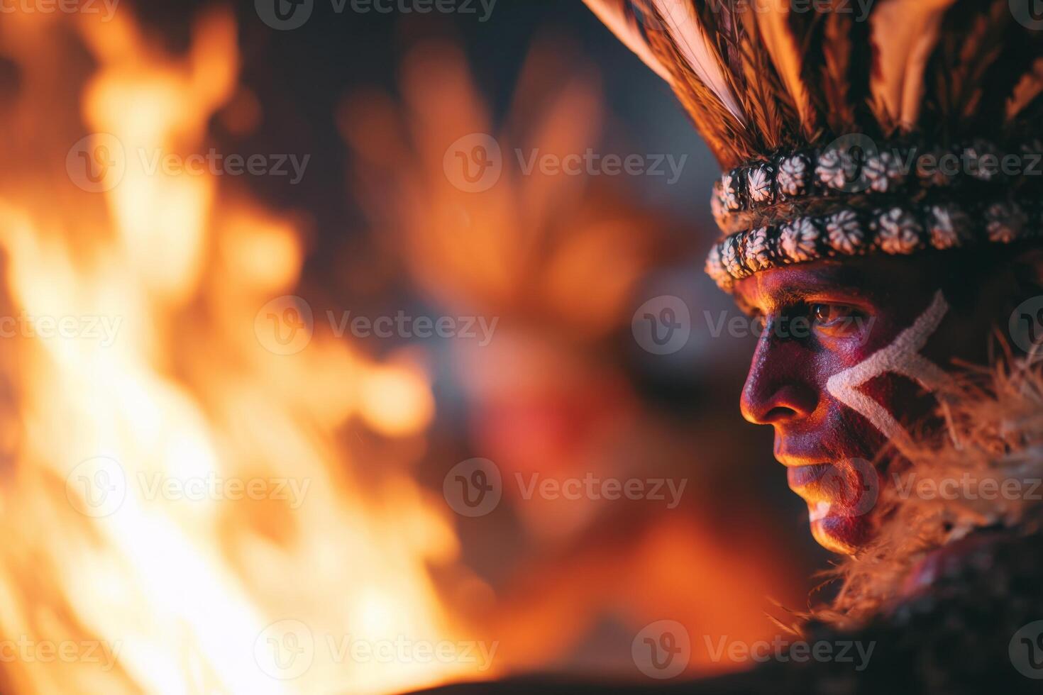 Indigenous man with tribal face paint and feathered headdress stands near a vibrant fire, showcasing cultural heritage and traditional practices in a captivating atmosphere photo