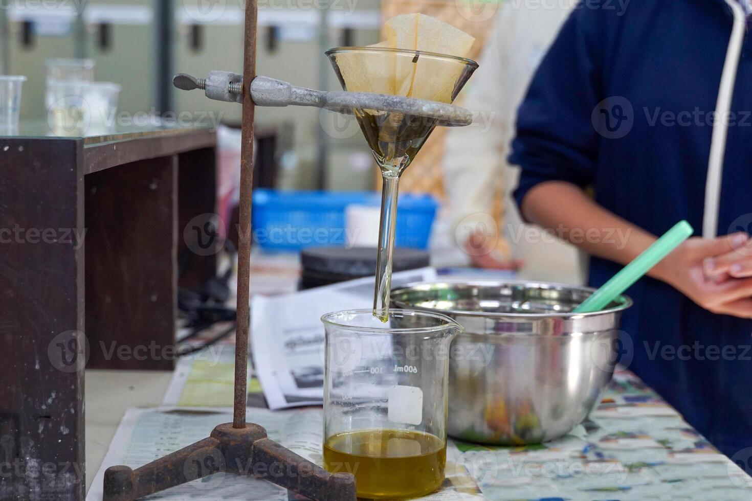 Experiment to separate mixed substances by pouring substances into a separator funnel through filter paper. photo