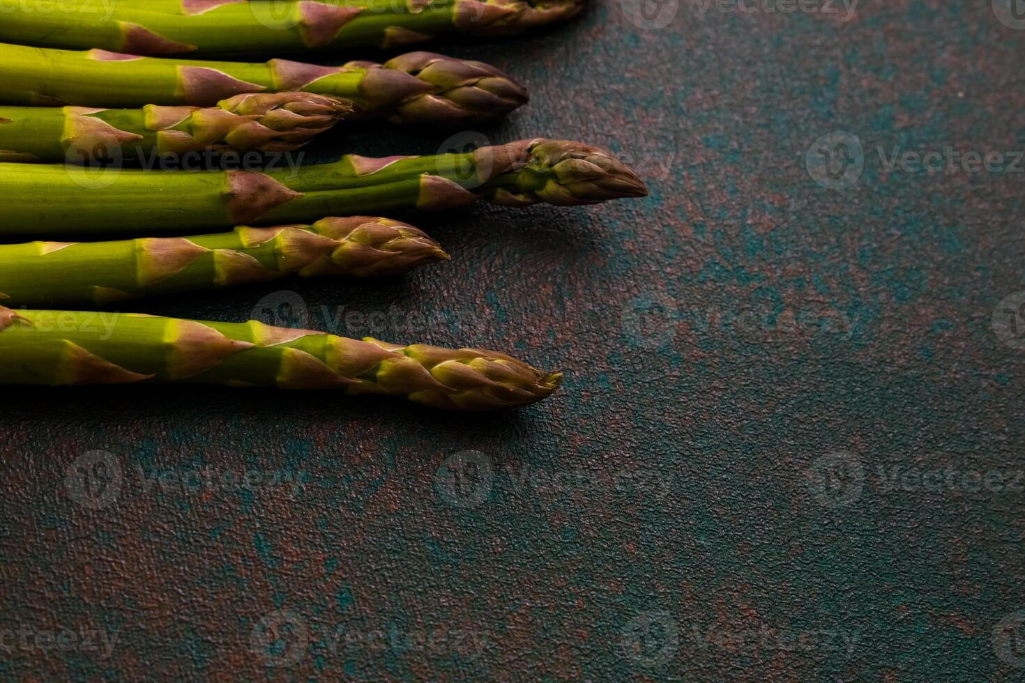 Fresh asparagus arranged on a textured surface ready for cooking or garnishing dishes photo